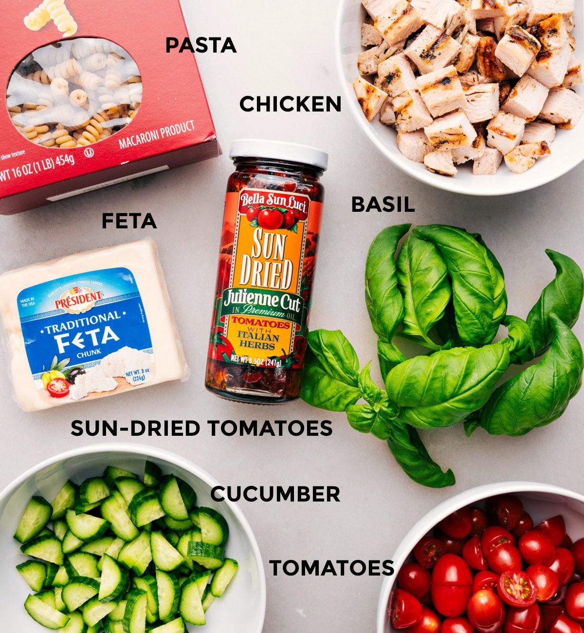 Everything’s prepped for easy assembly—pasta, chicken, basil, feta, sun-dried tomatoes, cucumber, and tomatoes.