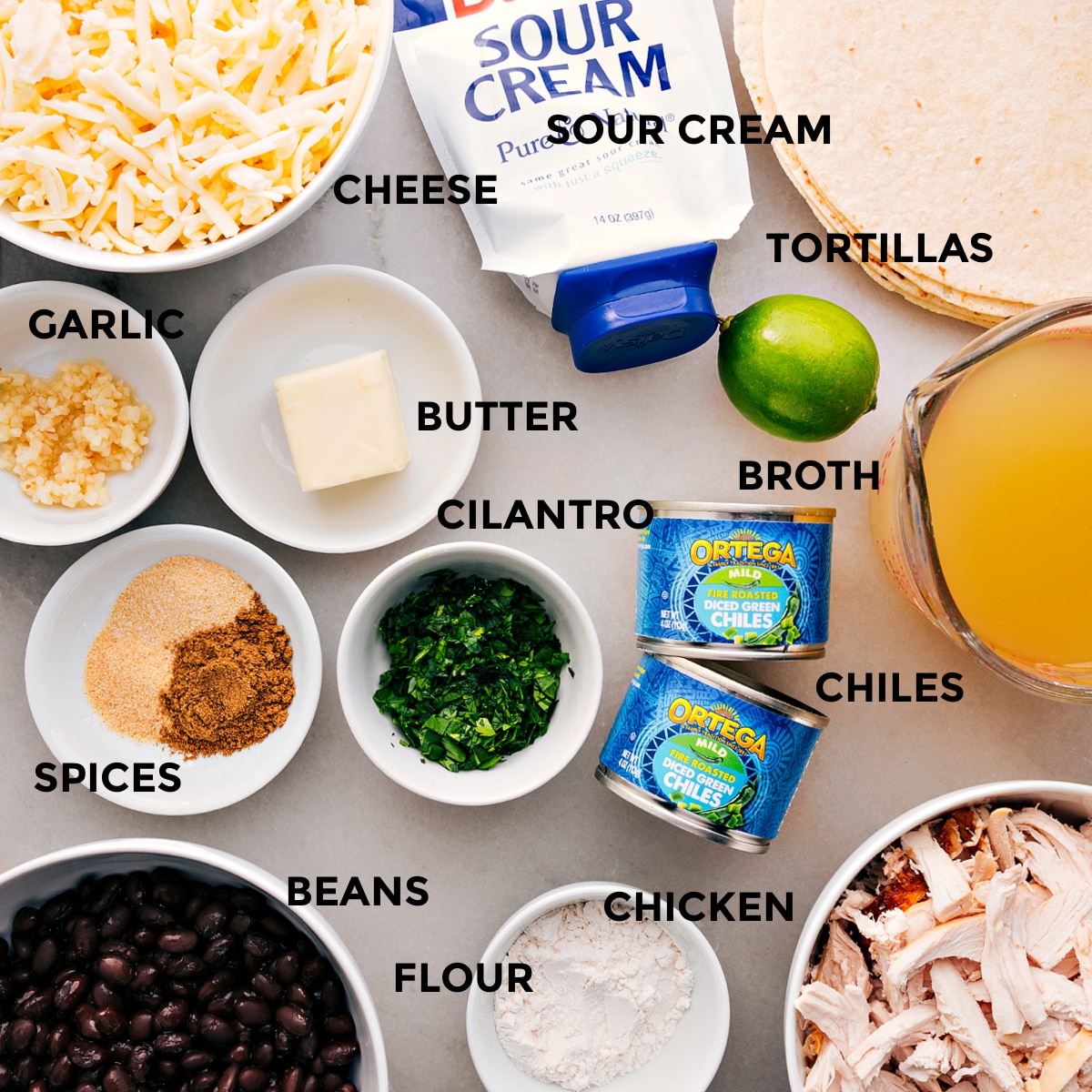 All the ingredients prepped and ready for easy assembly—cheese, tortillas, sour cream, broth, butter, cilantro, green chiles, garlic, spices, beans, chicken, and flour.