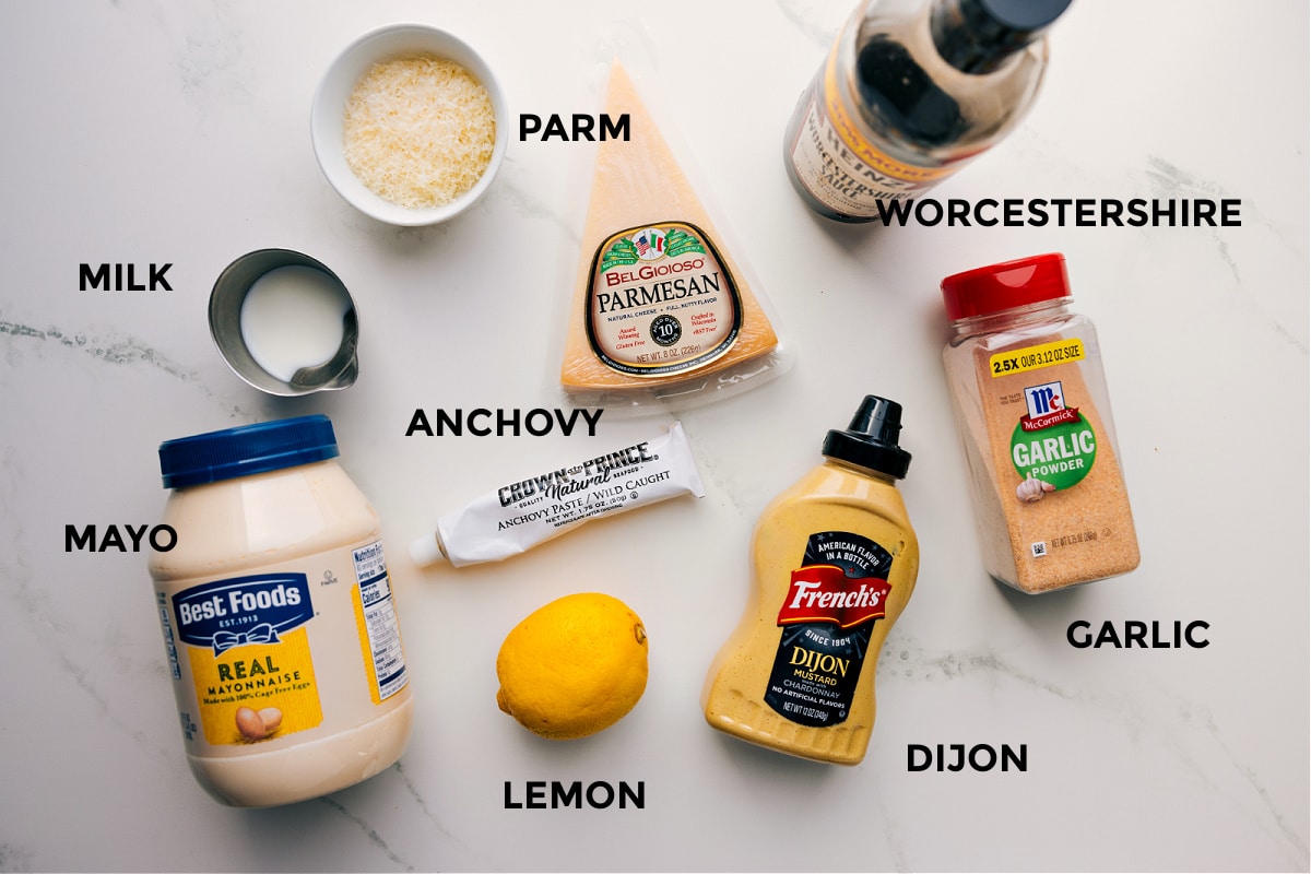 All the ingredients in this recipe prpped out for easy assembly including the parm, worcestershire, anchovy, lemon, dijon, garlic powder, milk, and mayo.