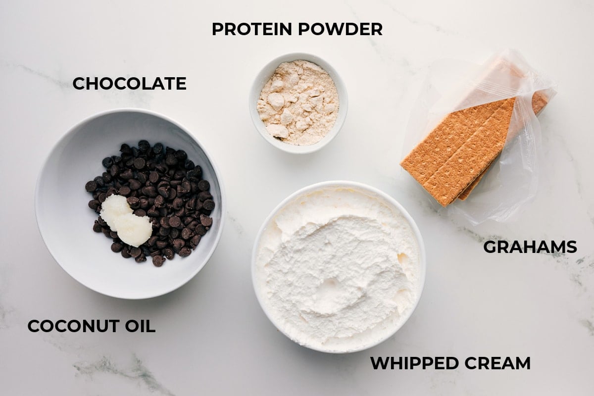All the ingredients prepped for easy assembly, including graham crackers, whipped cream, protein powder, chocolate, and coconut oil.