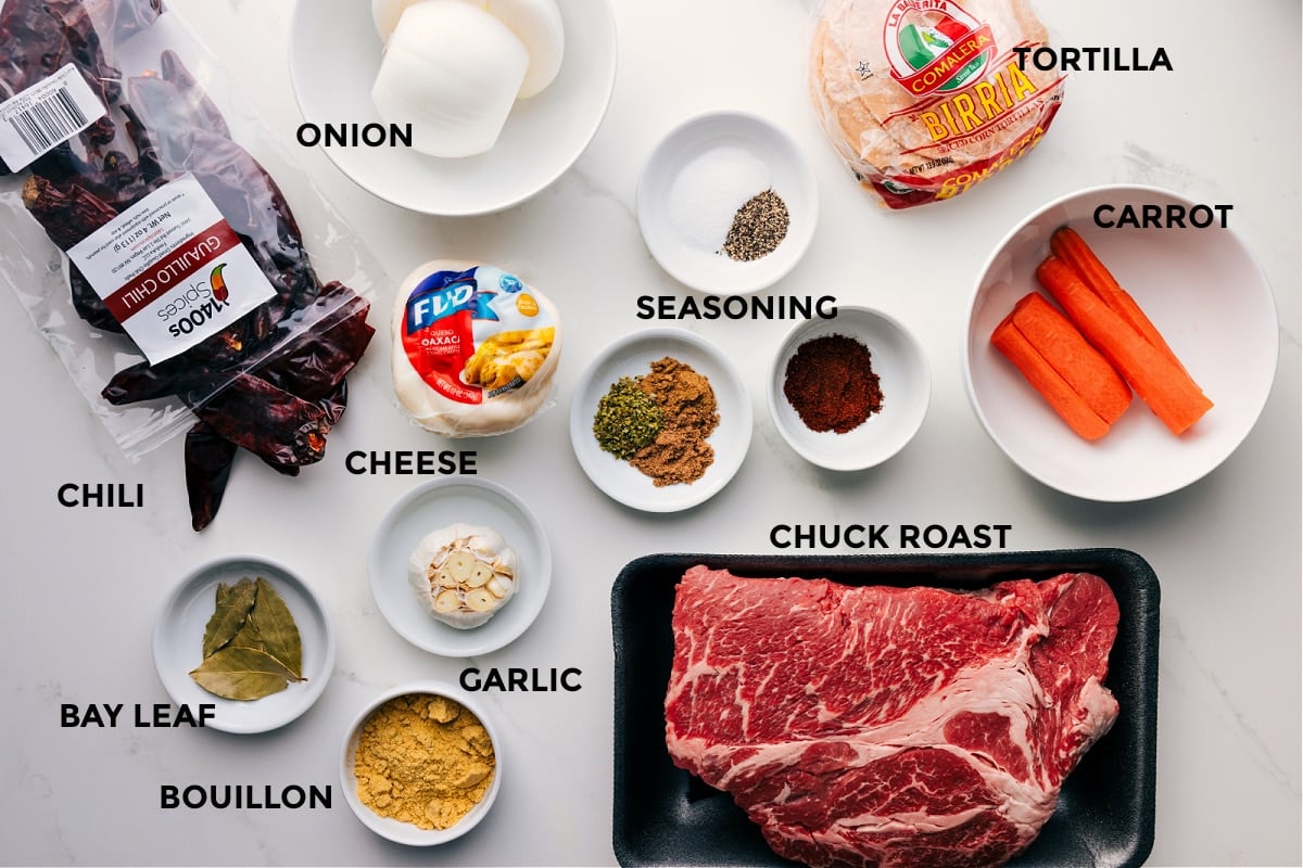 All the ingredients for this recipe prepped and ready for easy assembly: onion, chilis, tortillas, carrot, seasonings, cheese, chuck roast, garlic, and bouillon.