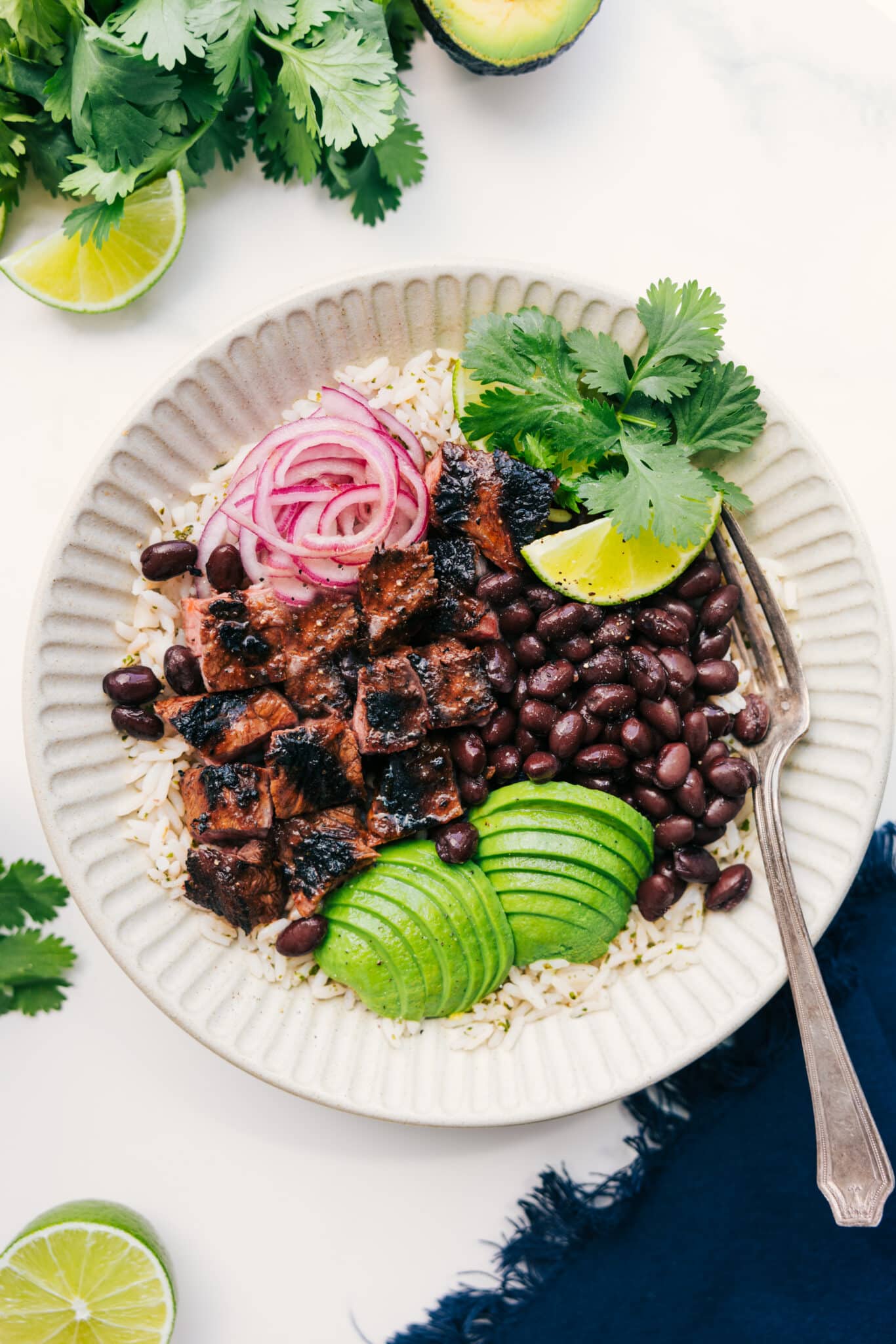 The Ultimate Meal Prep: Steak Bowls Steak bowl with rice, black beans, avocado, pickled onions, cilantro, and lime.