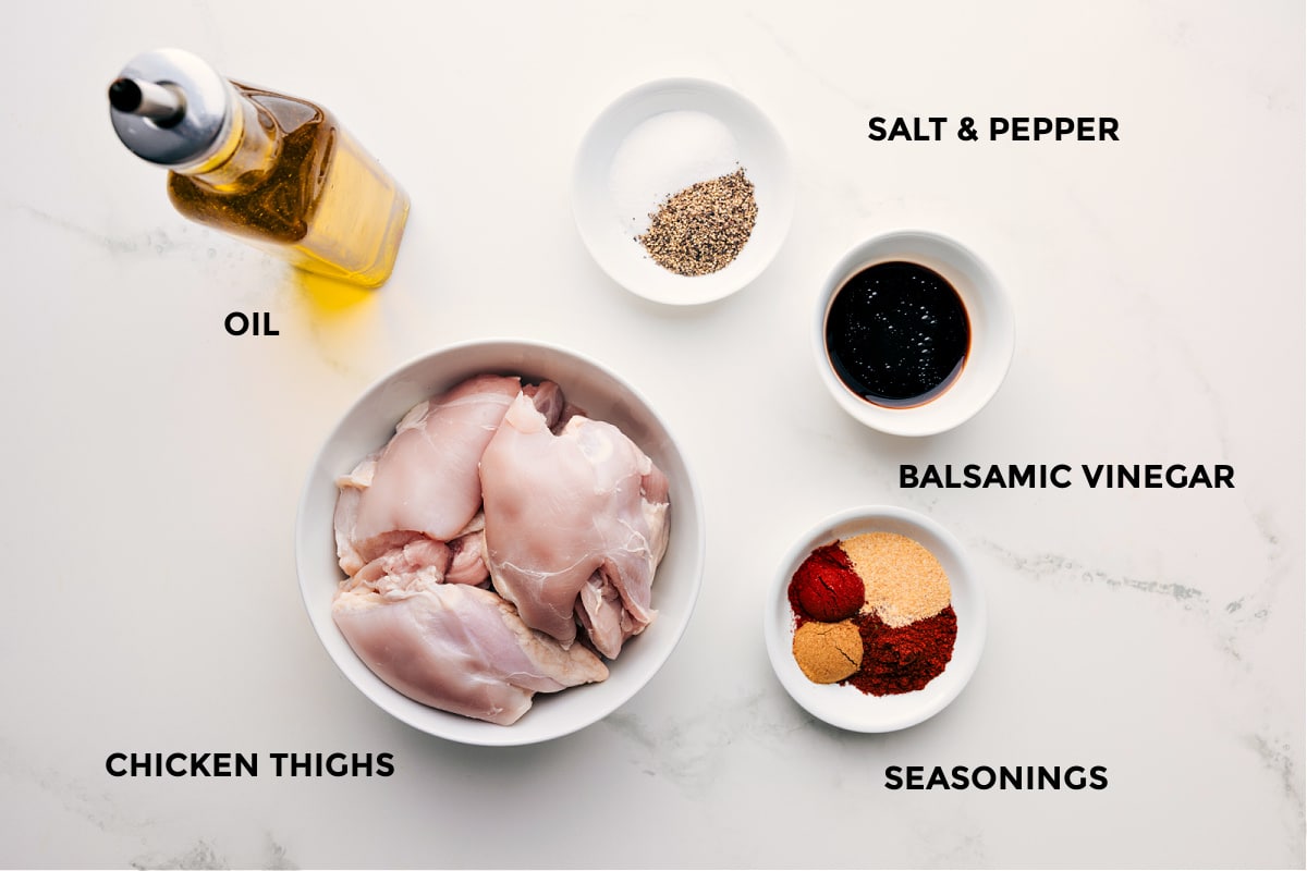 All the ingredients in this recipe prepped out for easy assembly including the oil, thighs, seasonings, and balsamic vinegar.