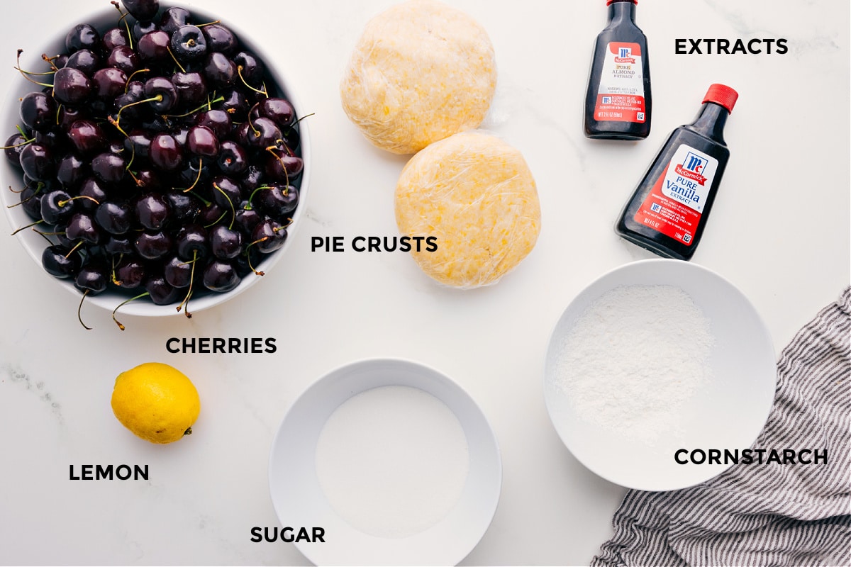 Prepped ingredients for this recipe including cherries, pie crusts, lemon, sugar, cornstarch, and extracts.