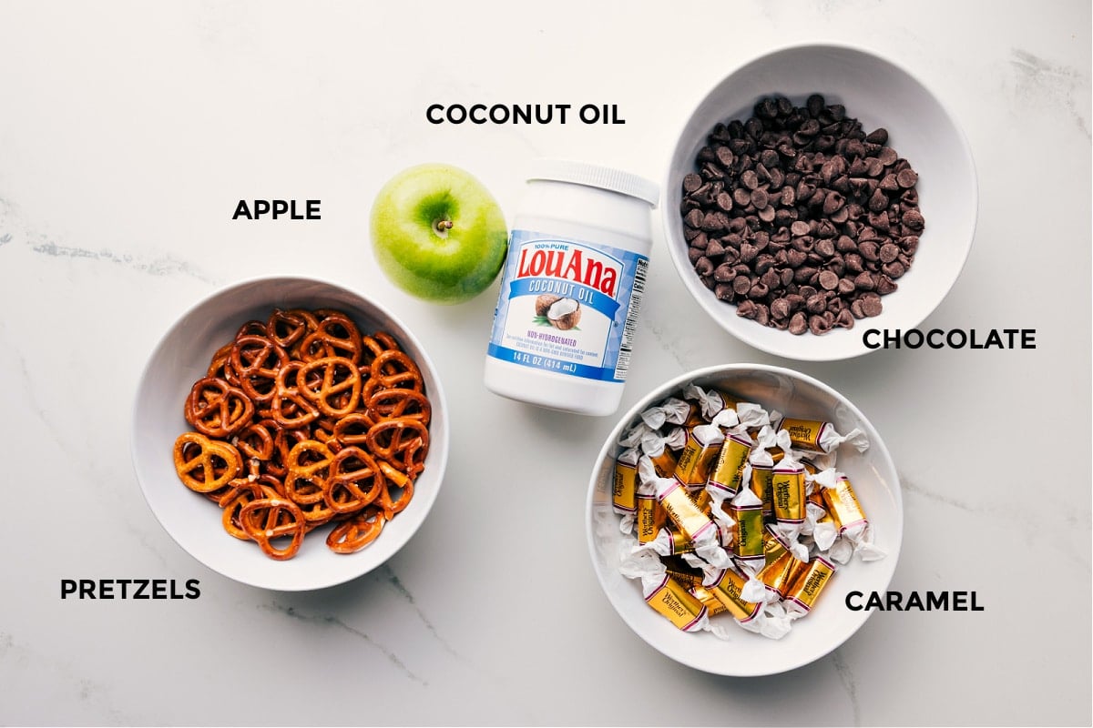 Ingredients in this recipe prepped out for easy assembly including the pretzels, apple, coconut oil, chocolate, and caramel.