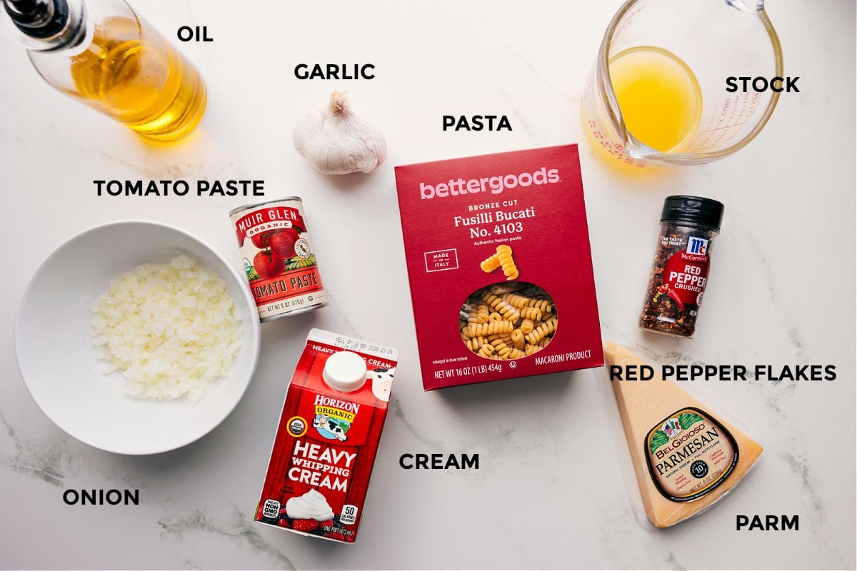 Ingredients In Creamy Tuna Pasta Recipe Ingredients for creamy tomato pasta prepped for easy assembly, including oil, garlic, onion, tomato paste, cream, pasta, stock, red pepper flakes, and Parmesan.
