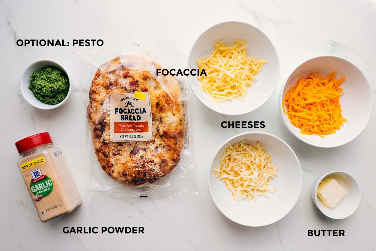 Ingredients laid out for easy assembly: bread, cheeses, butter, garlic powder, and optional pesto.