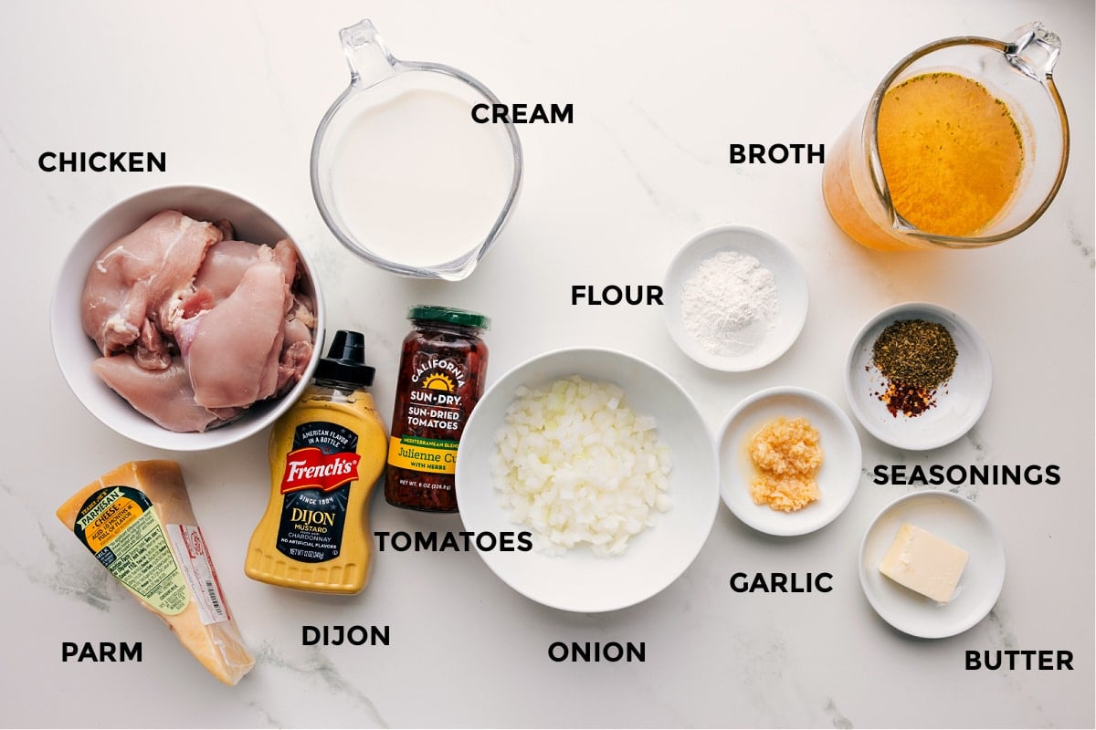 All the ingredients prepped for easy assembly, including chicken, Parmesan, Dijon, cream, tomatoes, onion, flour, garlic, seasonings, butter, and broth.