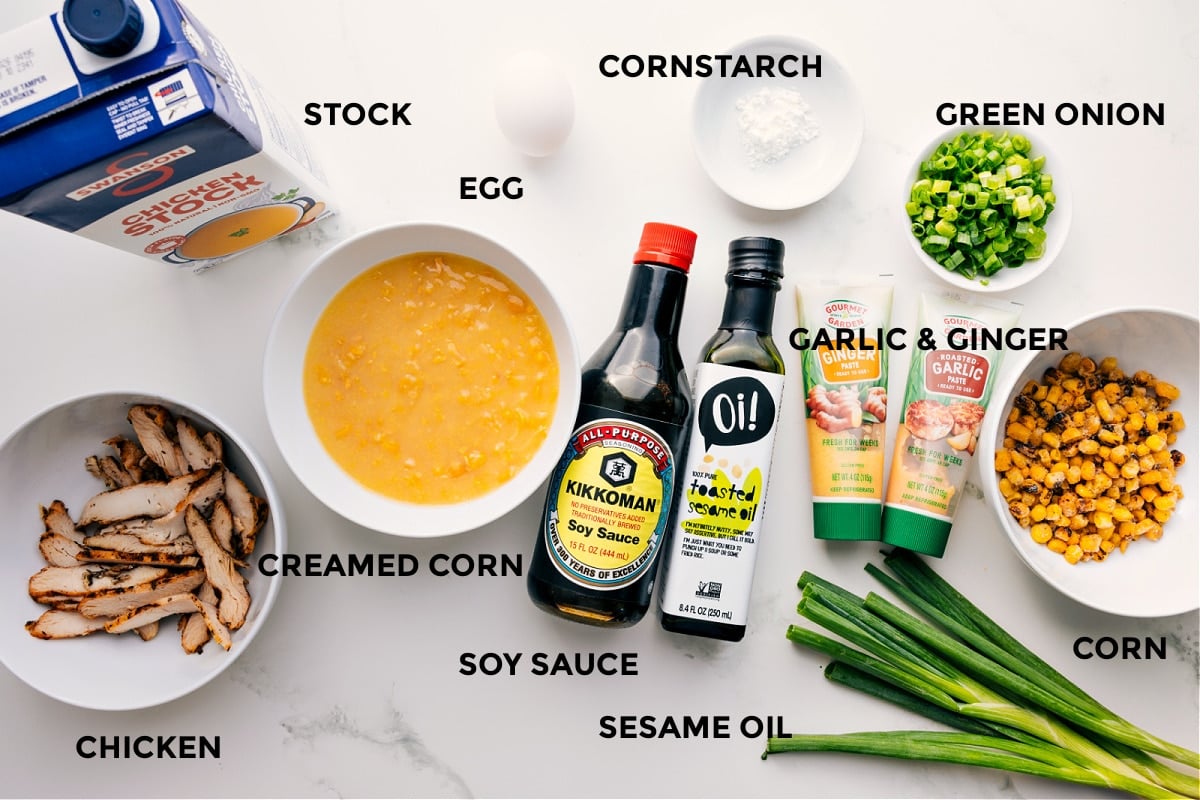 All the ingredients in this recipe prepped out for easy assembly including the stock, chicken, creamed corn, soy sauce, sesame oil, cornstarch, sesame oil, garlic, ginger, green onions, and corn.