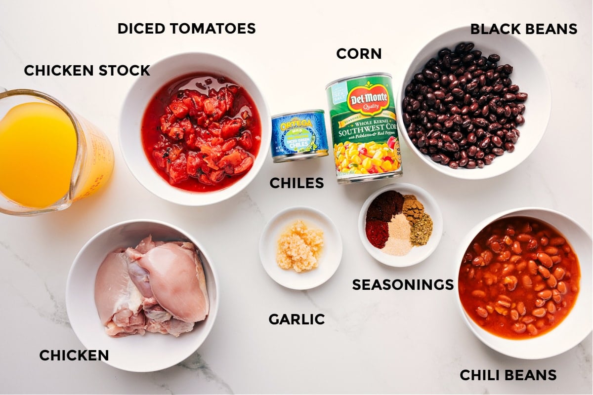All the ingredients for Chicken Taco Soup prepped for easy assembly, including stock, chicken, tomatoes, chiles, corn, garlic, seasonings, black beans, and chili beans.
