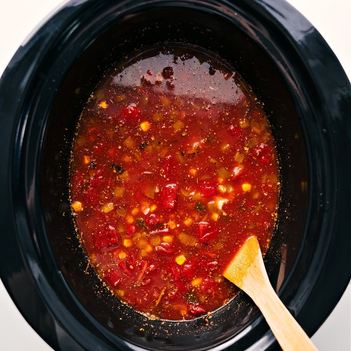 All the ingredients for chicken taco soup all dumped in a crockpot to slow cook.