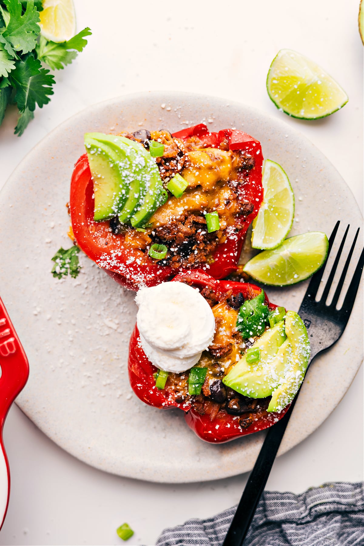 Stuffed pepper cut in half, topped with sour cream, avocado, cilantro, and jalapeños, ready to eat.