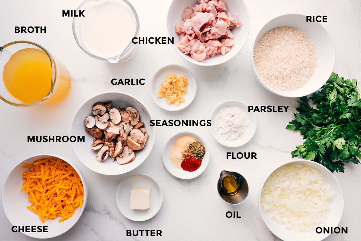 All the ingredients in this recipe prepped out for easy assembly including the broth, mushroom, milk, chicken, garlic, seasonings, flour, parsley, rice, oil, butter, carrots, and onion.