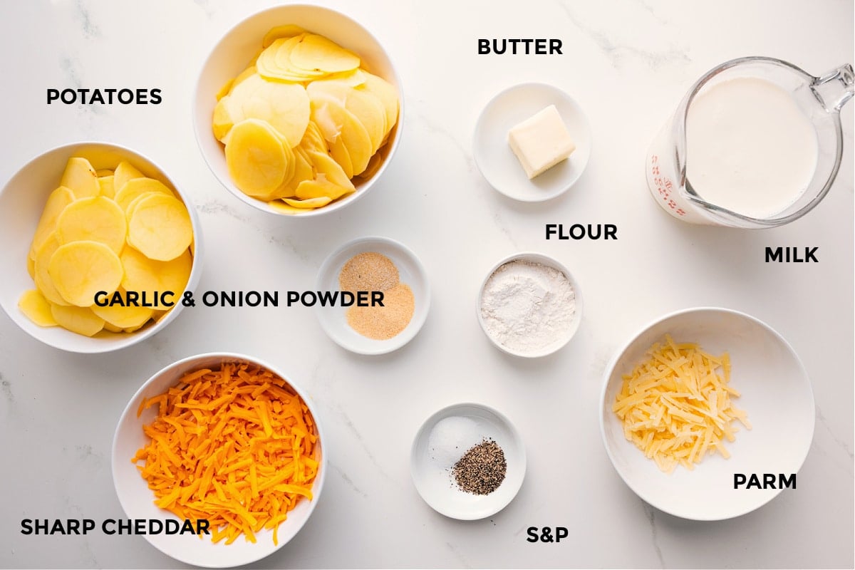 All the ingredients in this recipe prepped out for easy assembly including the potatoes, cheese, seasonings, flour, butter, parm, and milk.