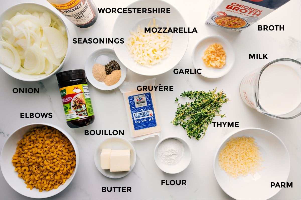 Prepped ingredients on the counter: onions, elbow macaroni, Worcestershire sauce, bouillon, butter, mozzarella, garlic, Gruyère, flour, thyme, Parmesan, milk, broth.