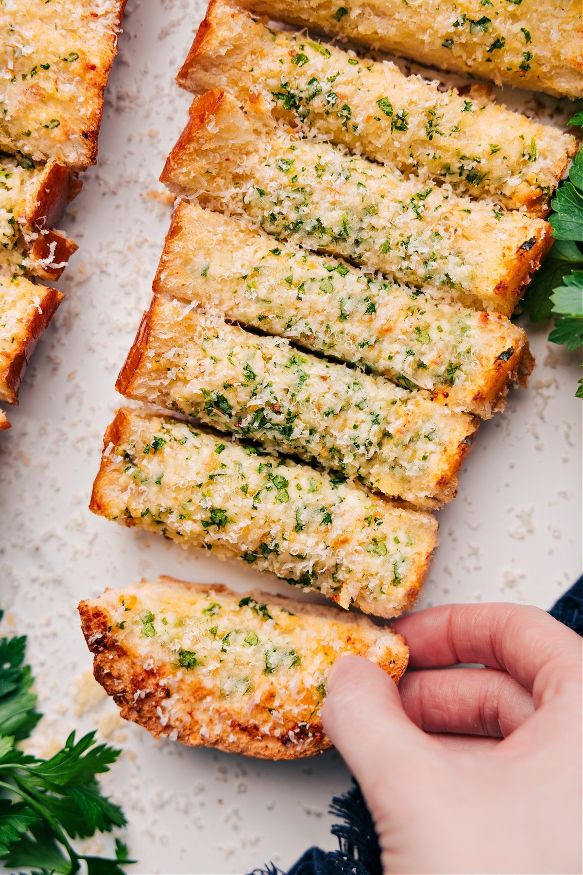 Garlic Bread Recipe cut into slices and topped with freshly grated Parmesan cheese, ready to serve.
