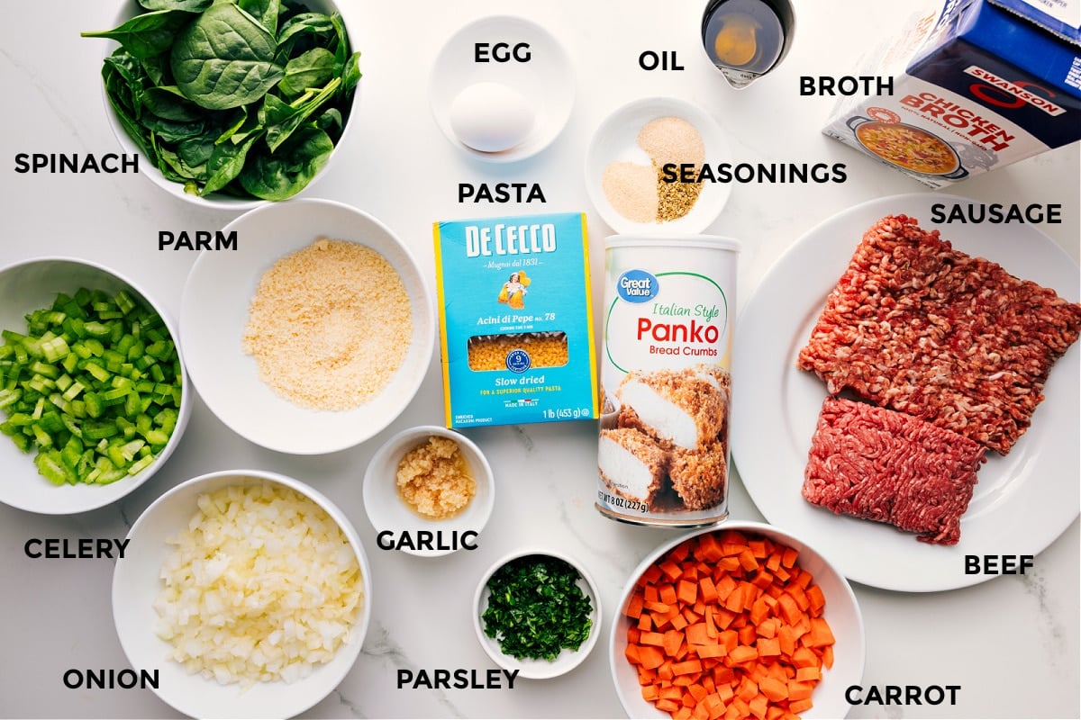Ingredients prepped for easy assembly including spinach, celery, onion, Parmesan, garlic, parsley, carrots, panko, beef, sausage, broth, seasonings, oil, egg, and pasta.
