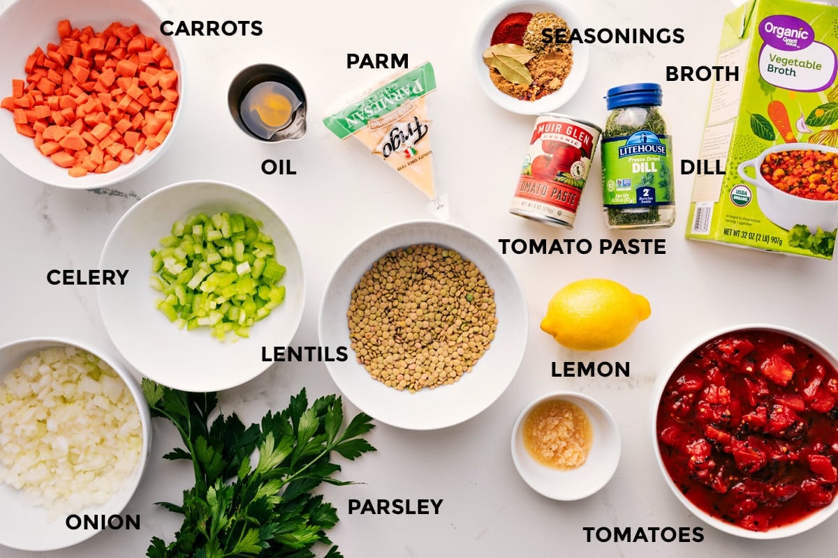 All the ingredients prepped and ready for easy assembly, including carrots, celery, onion, lentils, parsley, garlic, tomatoes, lemon, seasonings, tomato paste, dill, and broth.