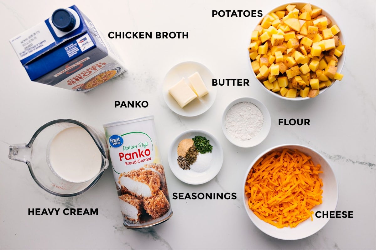 Ingredients In Crockpot Cheesy Potatoes Ingredients in this recipe prepped out for easy assembly including the chicken broth, heavy cream, Panko, seasonings, butter, flour, potatoes, and cheese.
