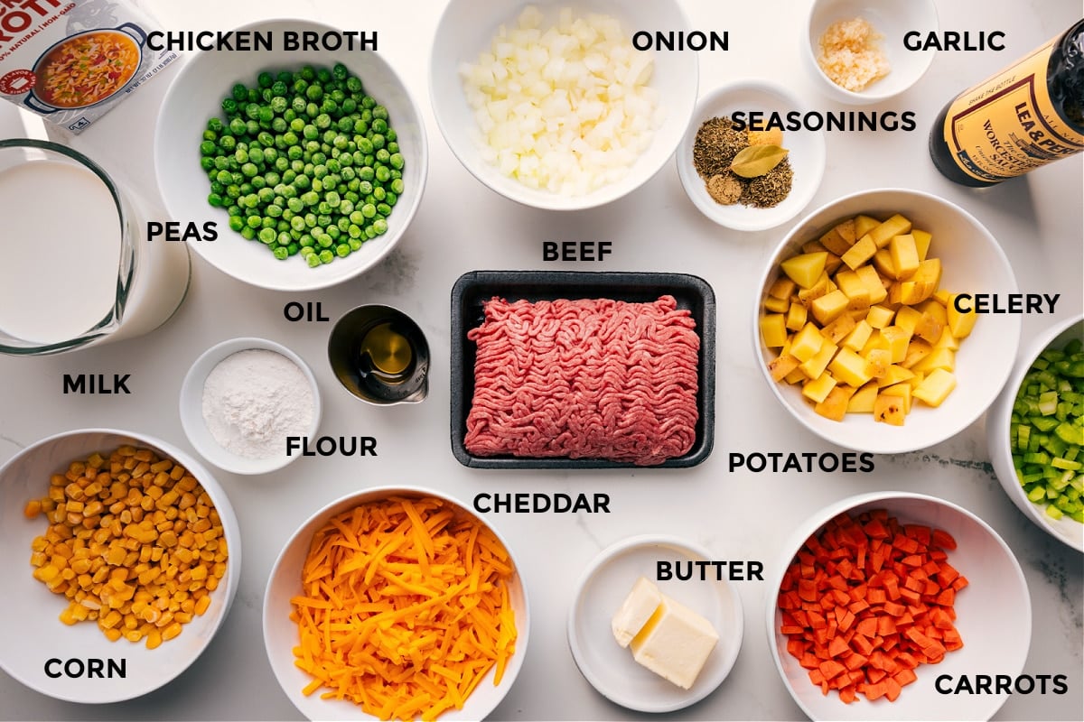 All the ingredients in this recipe prepped out for easy assembly including the chicken broth, peas, milk, corn, flour, oil, onion, seasonings, garlic, veggies, beef, and butter.