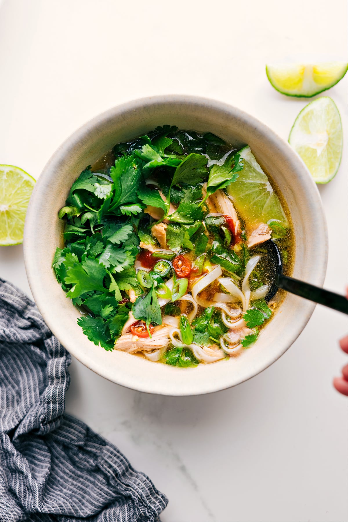 Chicken Pho Recipe Is Pure Comfort In A Bowl Chicken Pho Recipe in a bowl with fresh cilantro, lime, and peppers on top.