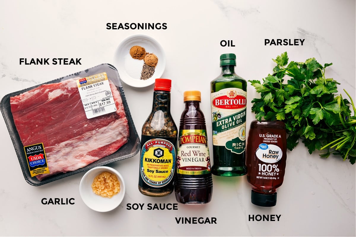 Ingredients In London Broil Recipe All the ingredients in this recipe prepped out for easy assembly including the steak, garlic, soy sauce, vinegar, honey, parsley, oil, and seasonings.