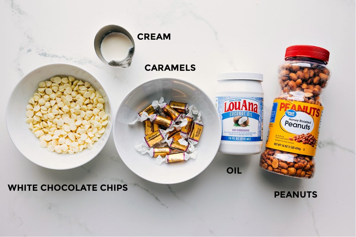 Ingredients in this recipe prepped out for easy assembly including the white chocolate chips, cream, caramels, oil, and peanuts.
