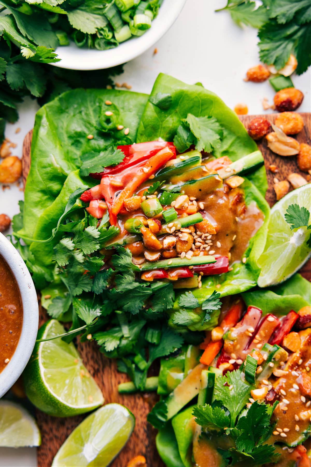 Delicious Peanut Chicken Lettuce Wraps Plated and Ready to Enjoy Chicken Lettuce Wraps topped with fresh cilantro, green onions, peanut dressing, and sesame seeds.