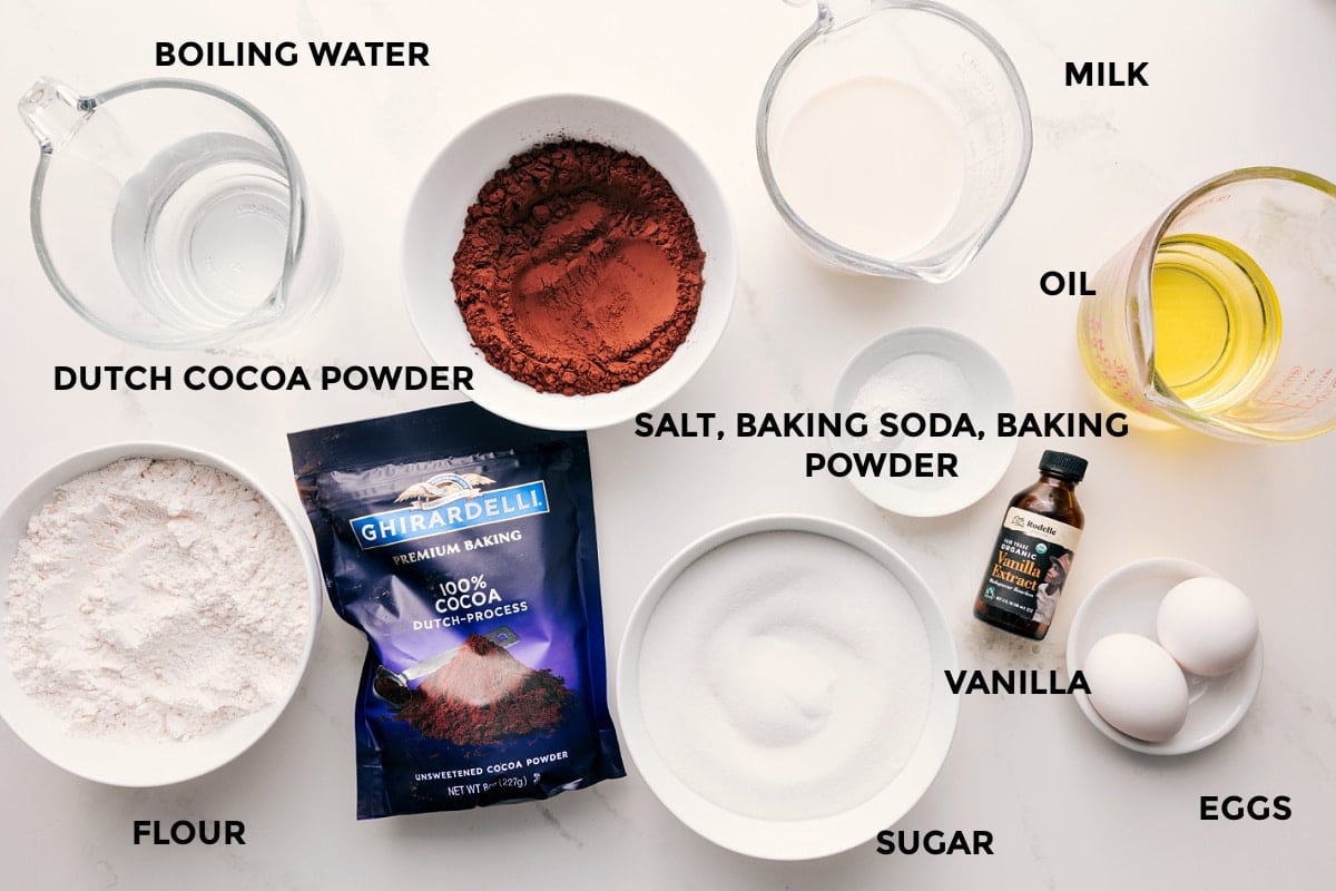 All the ingredients in this recipe prepped out for easy assembly including the boiling water, flour, cocoa powder, salt, baking soda, baking powder, sugar, vanilla, eggs, oil, and milk.