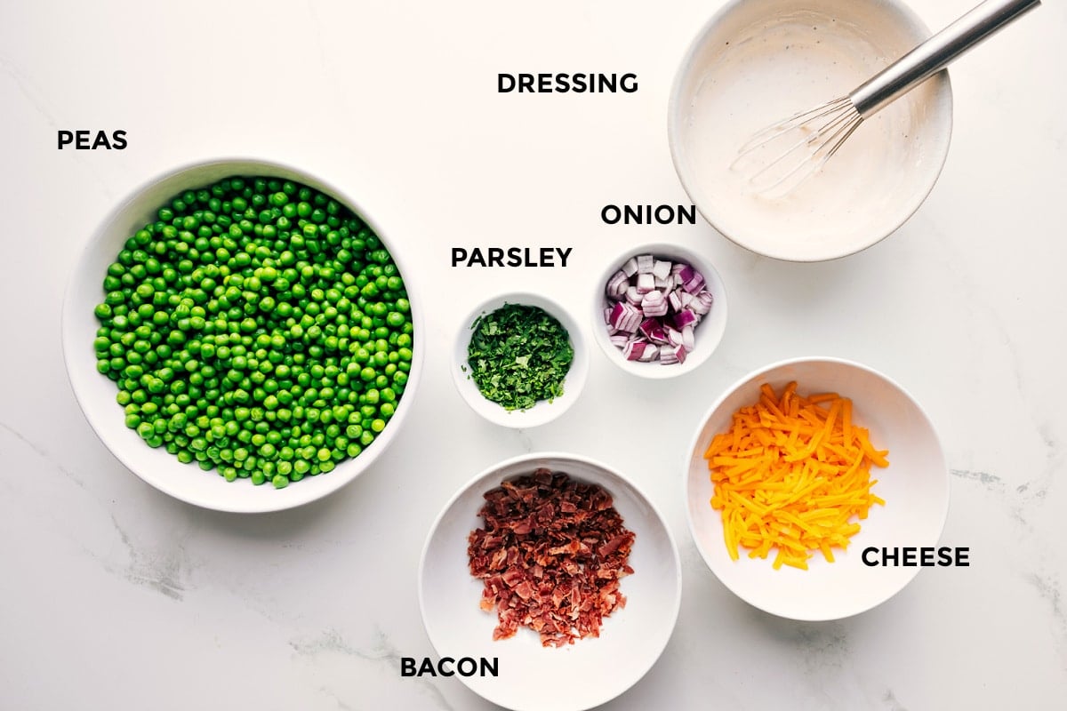 All the ingredients in this recipe prepped out for easy assembly including the peas, parsley, onion, cheese, bacon, and dressing.
