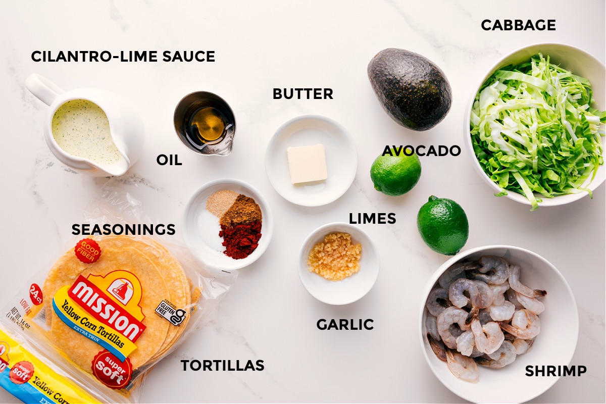 Ingredients In Shrimp Tacos All the ingredients in this recipe prepped out for easy assembly including the cilantro lime sauce, seasonings, tortillas, butter, garlic, limes, avocado, shrimp, and cabbage.