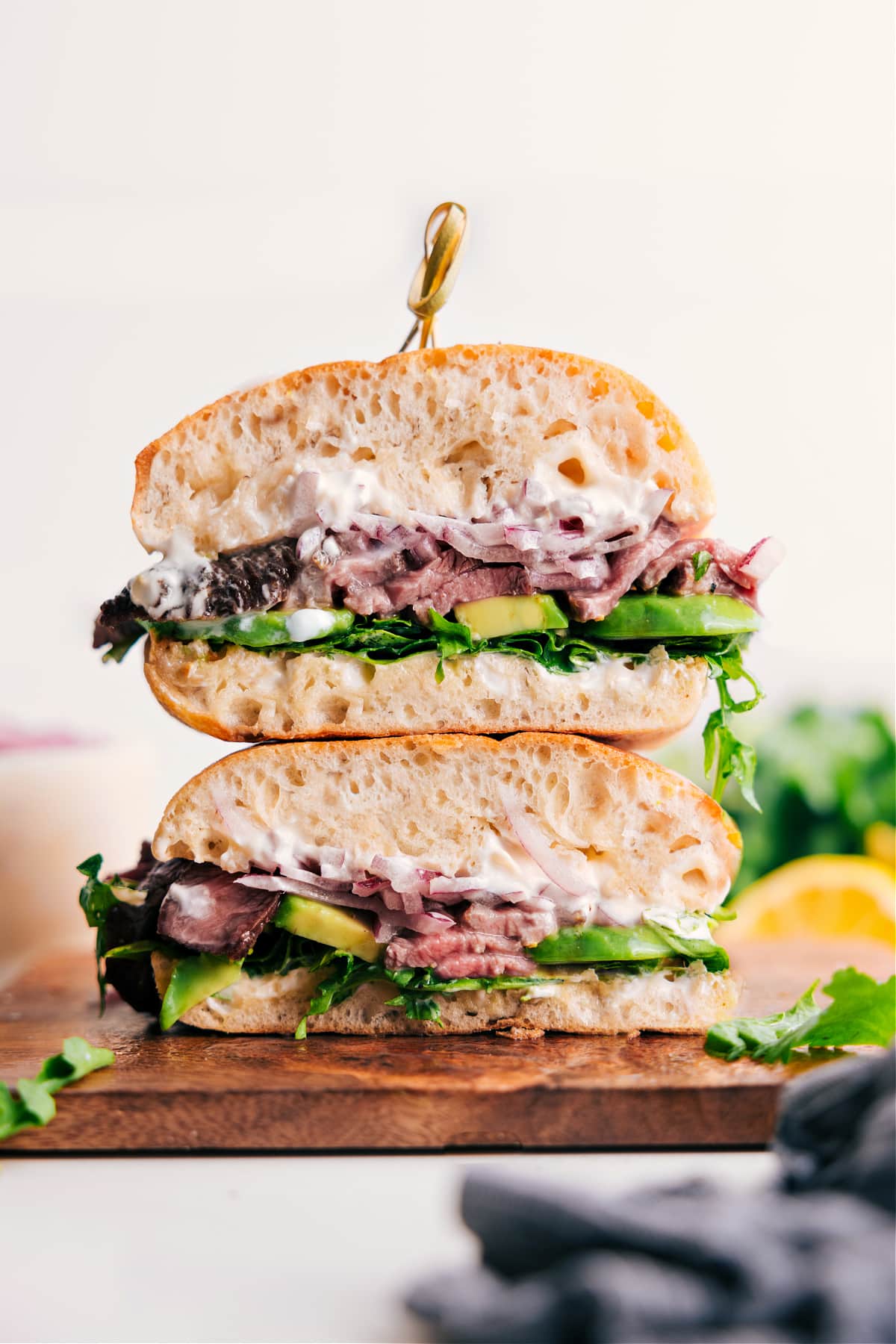 The Ultimate Steak Sandwich Recipe Steak Sandwich Recipe stacked on top of each other with avocado, lettuce, and aioli sauce.