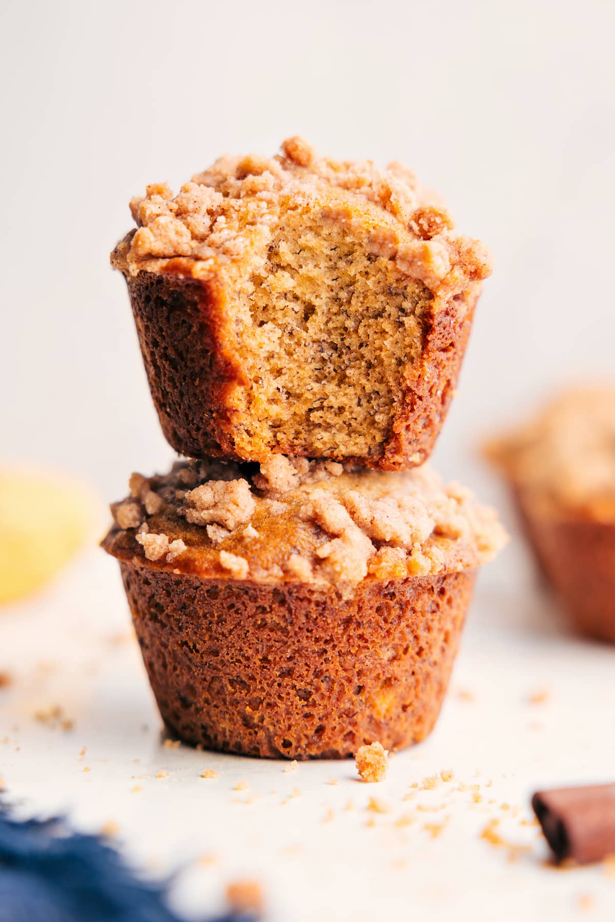 Banana Crumb Muffins Fresh Out Of The Oven Banana crumb muffins stacked with a bite taken out, showing the soft inside and crumb topping.