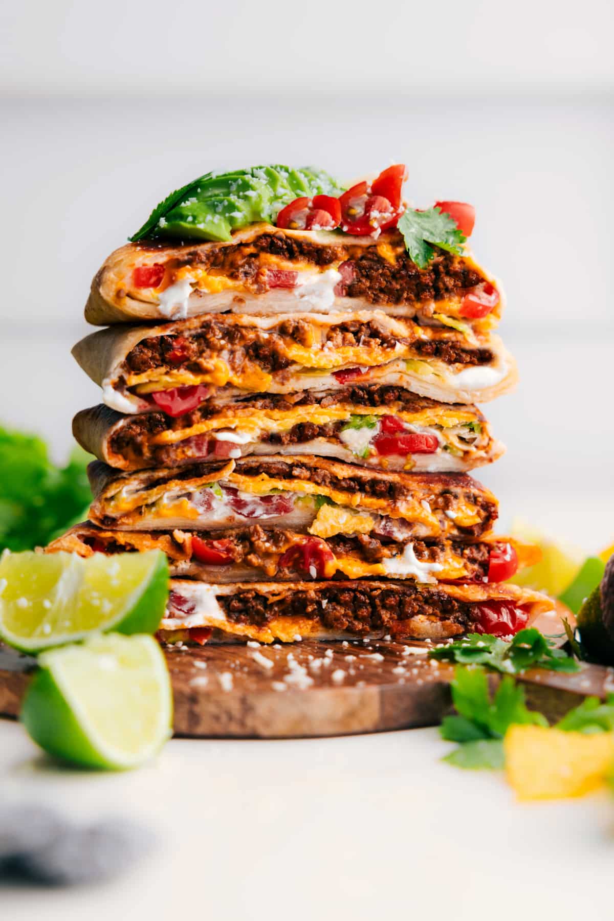 Crunchwrap Supreme Recipe cut in half and stacked on top of each other, finished with fresh toppings like tomatoes and avocado.