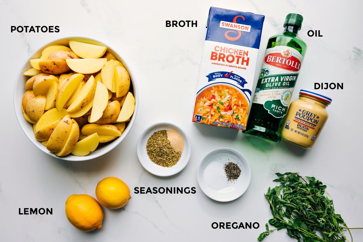 Ingredients In Greek Potatoes Recipe All the ingredients prepped and ready to assemble, including potatoes, lemons, seasonings, broth, oil, and Dijon.