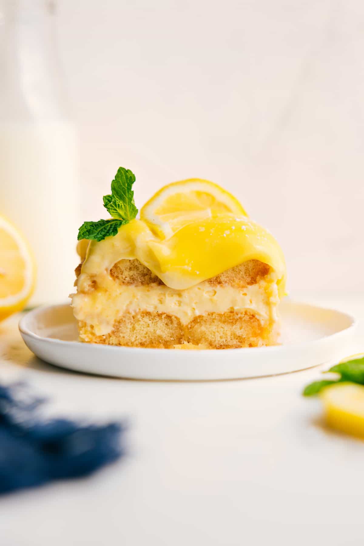 A Slice Of The Most Decadent And Delicious Lemon Tiramisu Lemon Tiramisu topped with fresh lemon curd, a lemon slice, and mint.