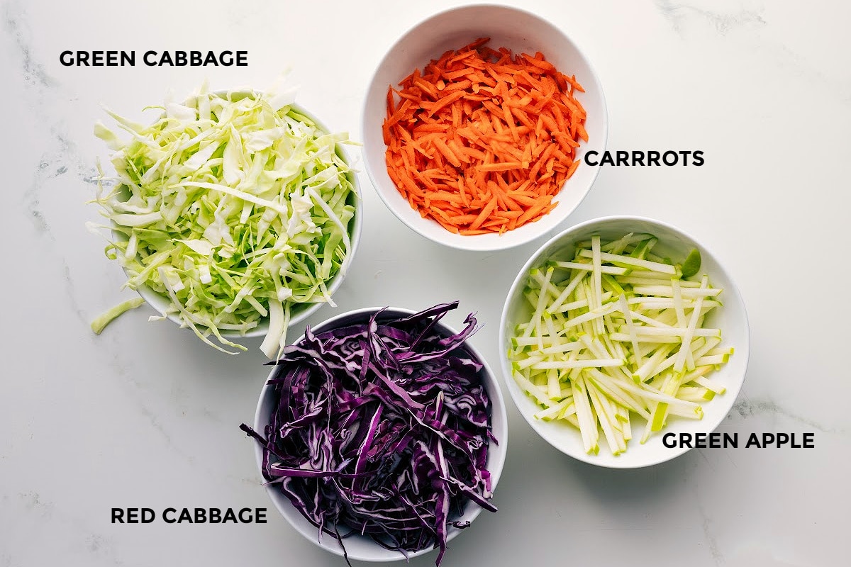 Easy Coleslaw Recipe Ingredients The ingredients in this recipe prepped out for easy assembly including the green cabbage, red cabbage, carrots, and green apple.