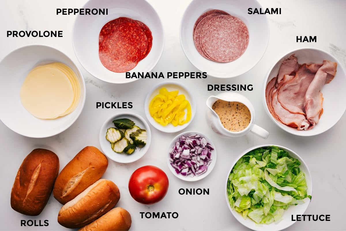 Ingredients In This Chopped Italian Sandwich All the ingredients in this recipe prepped out for easy assembly including provolone, pepperoni, salami, ham, rolls, pickles, banana peppers, tomato, onion, dressing, and lettuce.