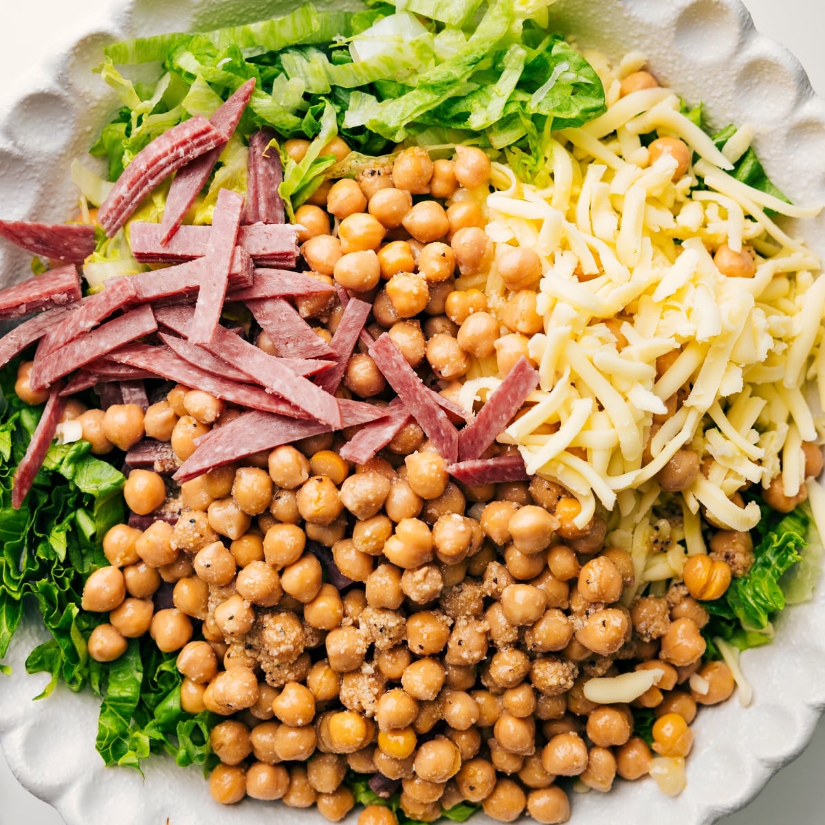 La Scala Chopped Salad In A Bowl Ready To Be Tossed The salad ingredients in a bowl with dressing, ready to be tossed.