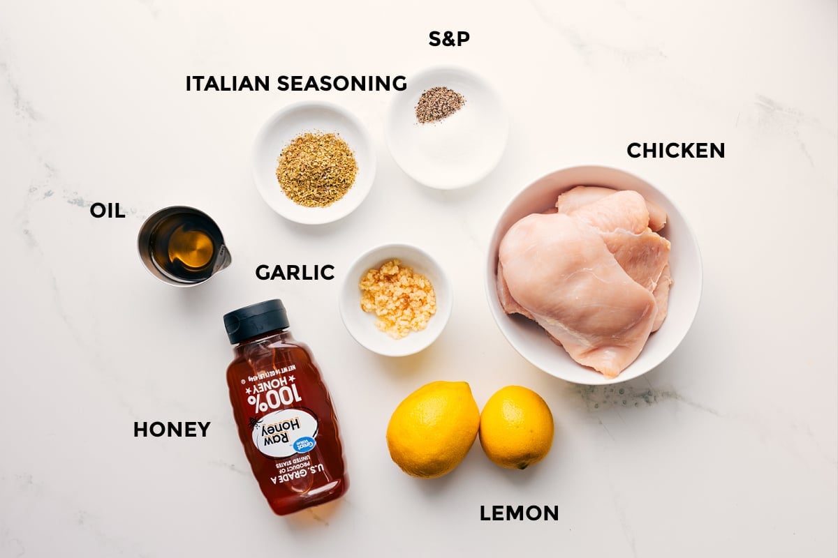 Lemon Garlic Chicken Marinade Ingredients The ingredients in this recipe prepped out for easy assembly including the oil, honey, seasonings, garlic, chicken, and lemons.
