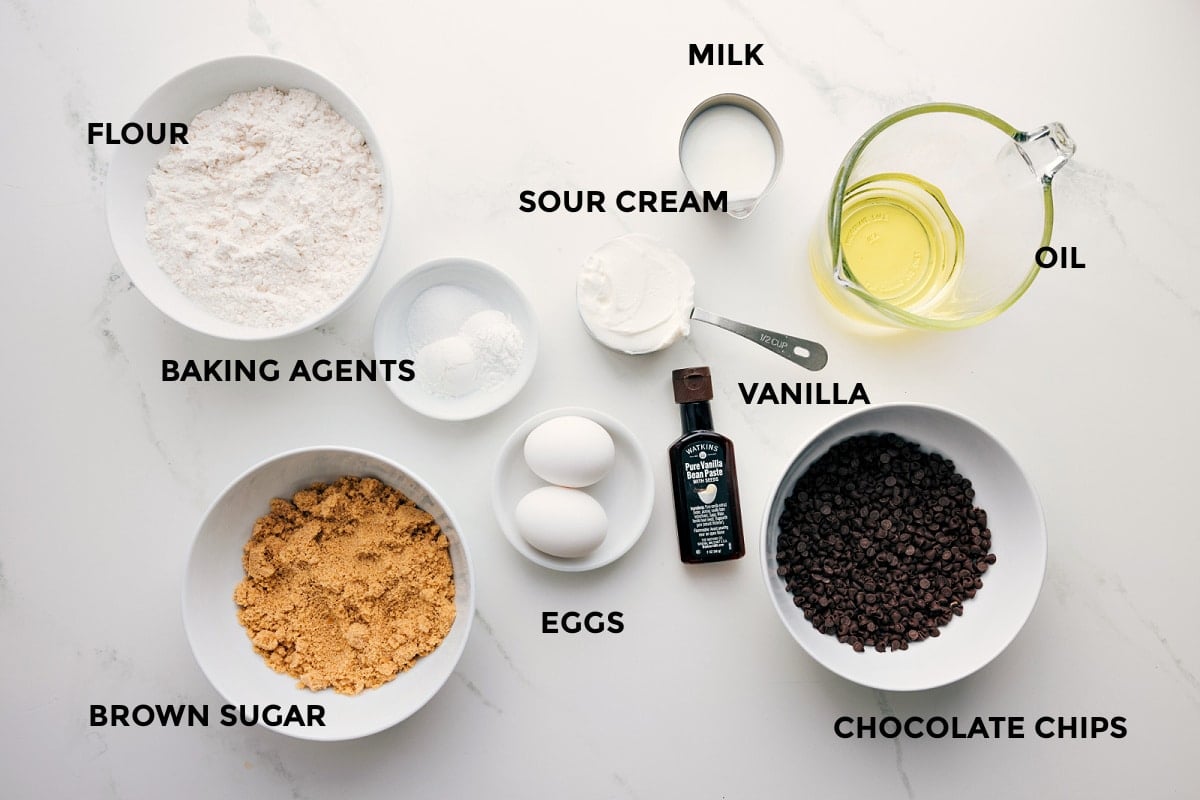 Ingredients In Mini Muffins All the ingredients in this recipe prepped out for easy assembly including the flour, baking agents, brown sugar, eggs, sour cream, milk, vanilla, chocolate chips, and oil.