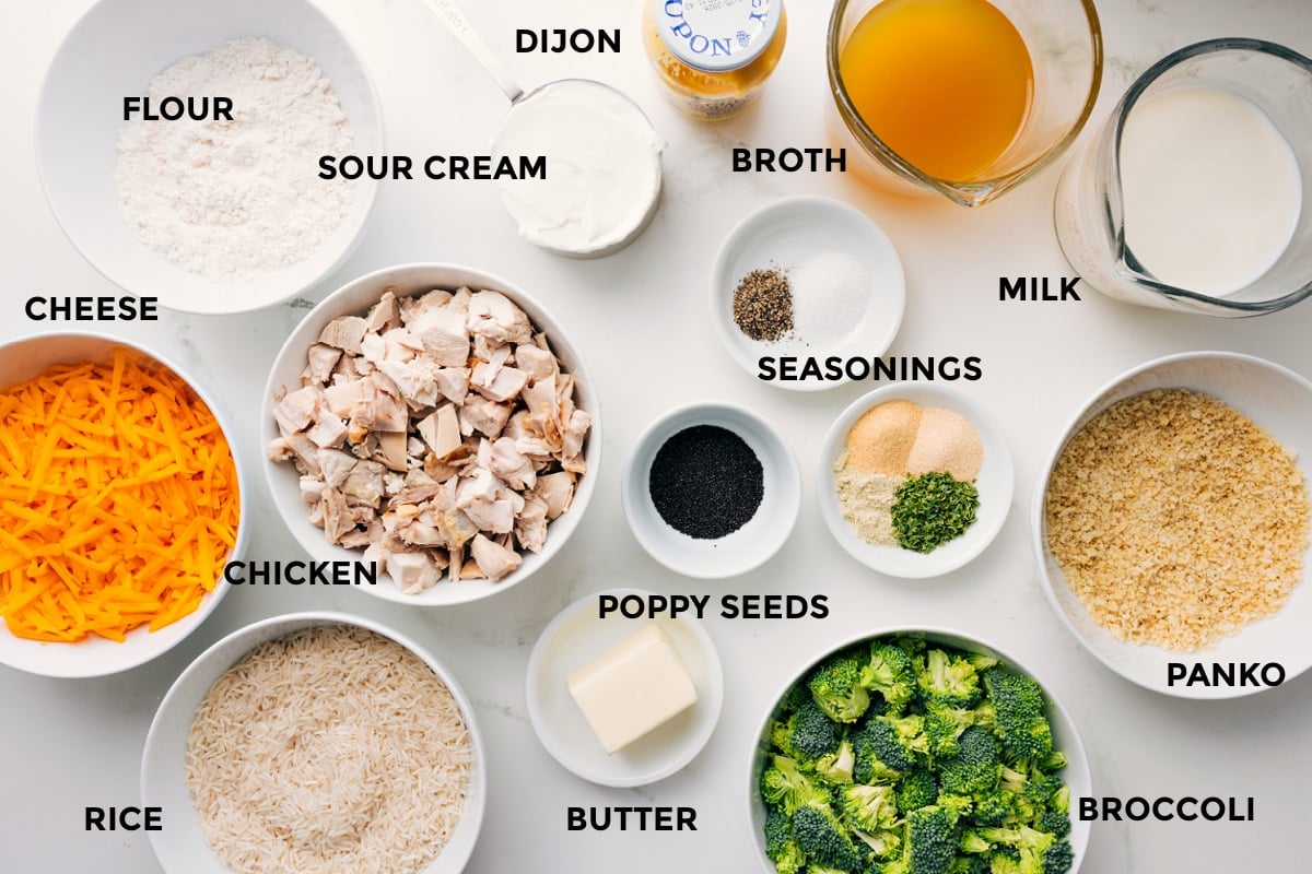 Ingredients In This Poppy Seed Chicken Casserole Ingredients for Poppy Seed Chicken Casserole prepped for assembly, including cheese, rice, chicken, broccoli, panko, and sauce ingredients.