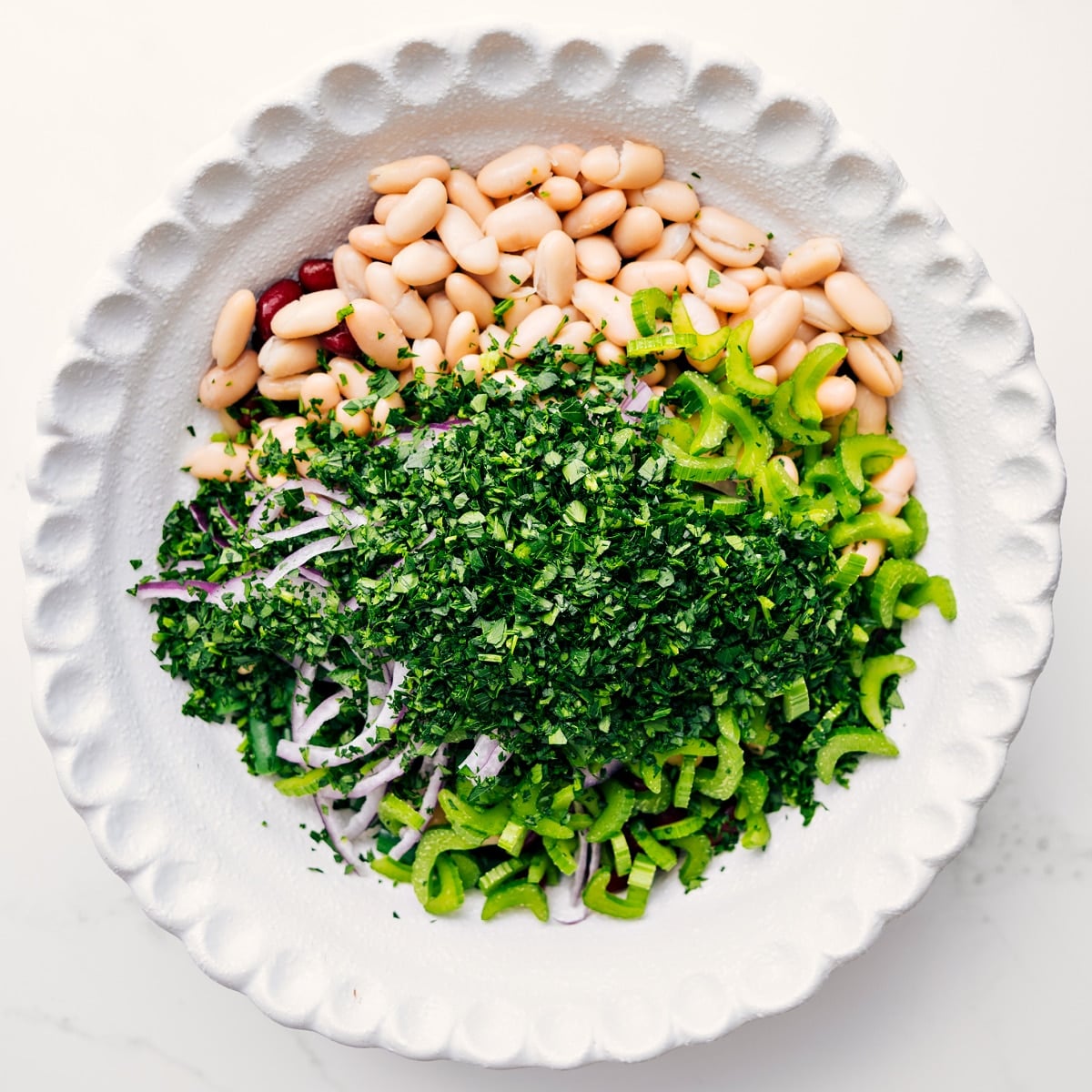 How To Make This Three Bean Salad Three bean salad ingredients added to a bowl, ready to be tossed with dressing.