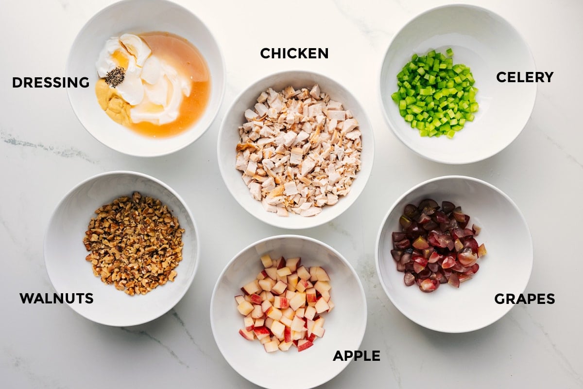 Ingredients In This Waldorf Chicken Salad All the ingredients prepped out for easy assembly including the dressing, walnuts, apple, chicken, grapes, and celery.