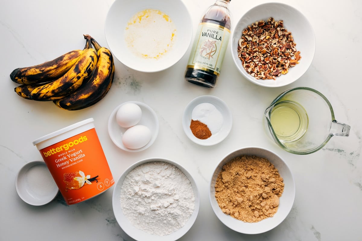 Ingredients In This Banana Nut Bread Recipe All the ingredients in this recipe prepped out for easy assembly including the bananas, yogurt, flour, sugar, oil, nuts, vanilla, spices, baking agents, eggs, and butter.