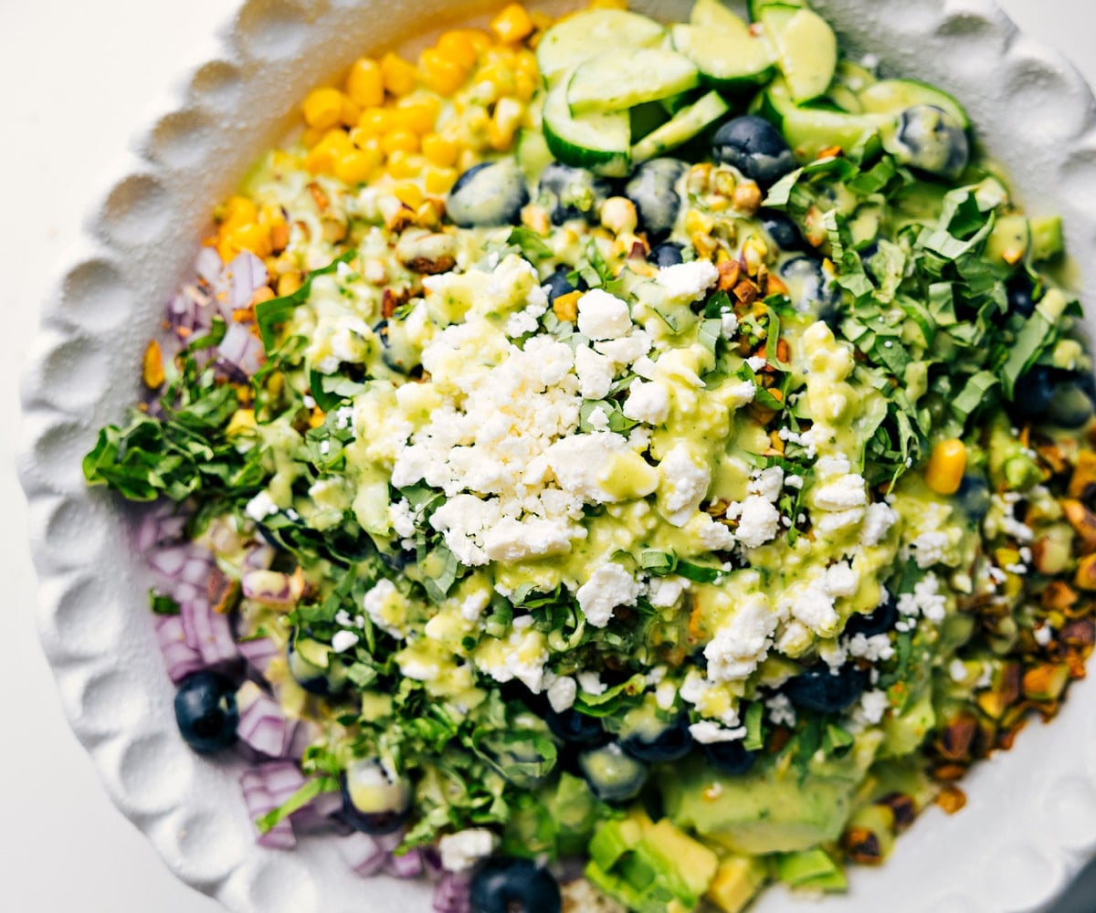 How To Make This Blueberry Salad Blueberry salad ingredients added to a bowl with dressing drizzled over the top.