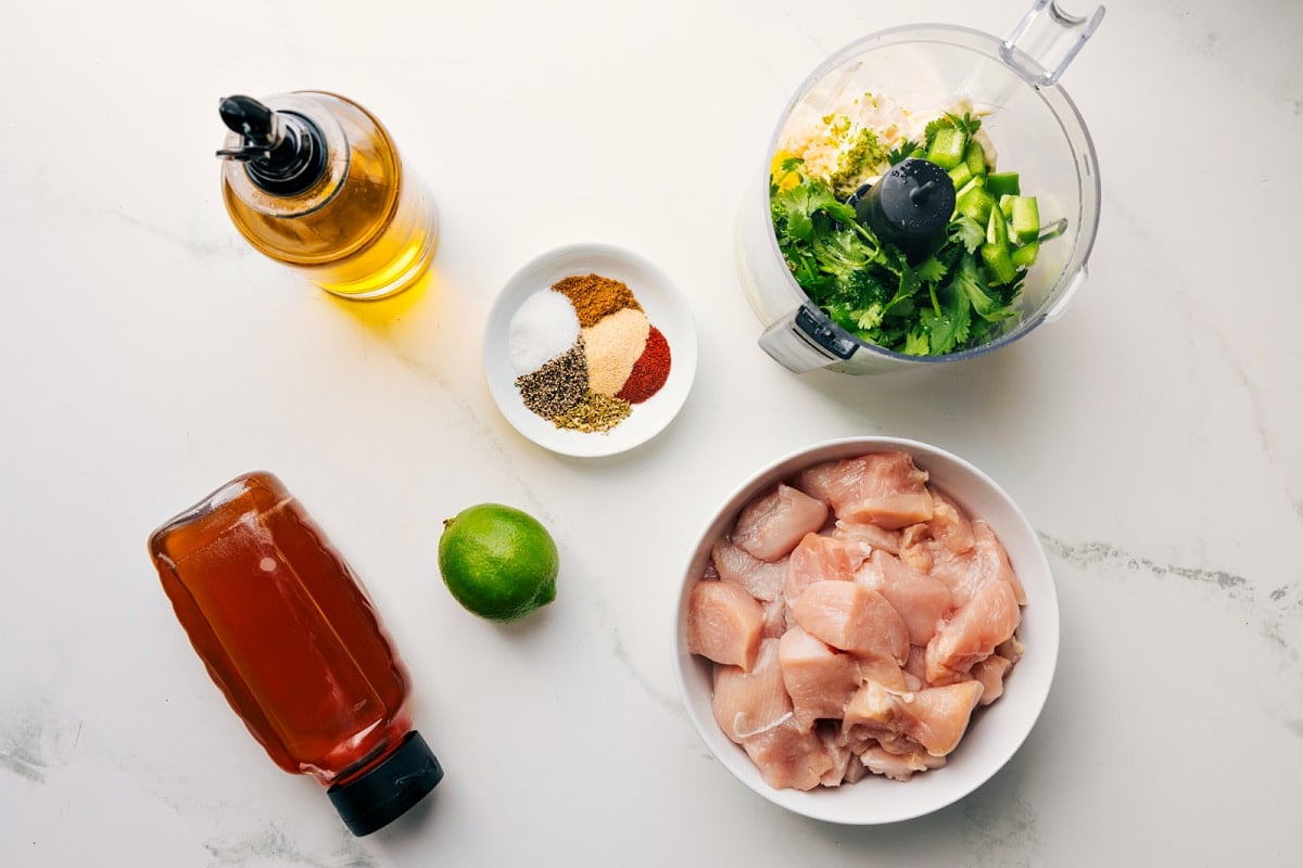 All the ingredients in this recipe prepped out for easy assembly including the honey, oil, lime, seasonings, chicken, and sauce.