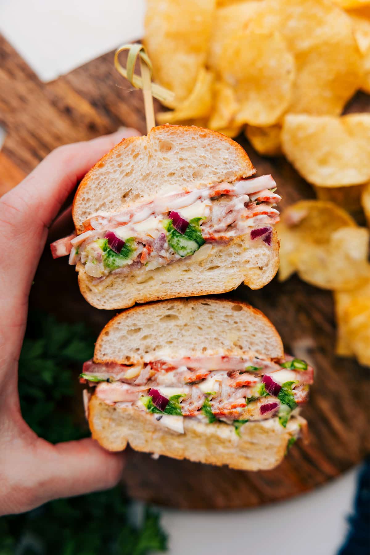 Chopped Italian Sandwich Stacked On Top Of Eachother Chopped Italian Sandwich cut in half and stacked on top of each other on a cutting board.
