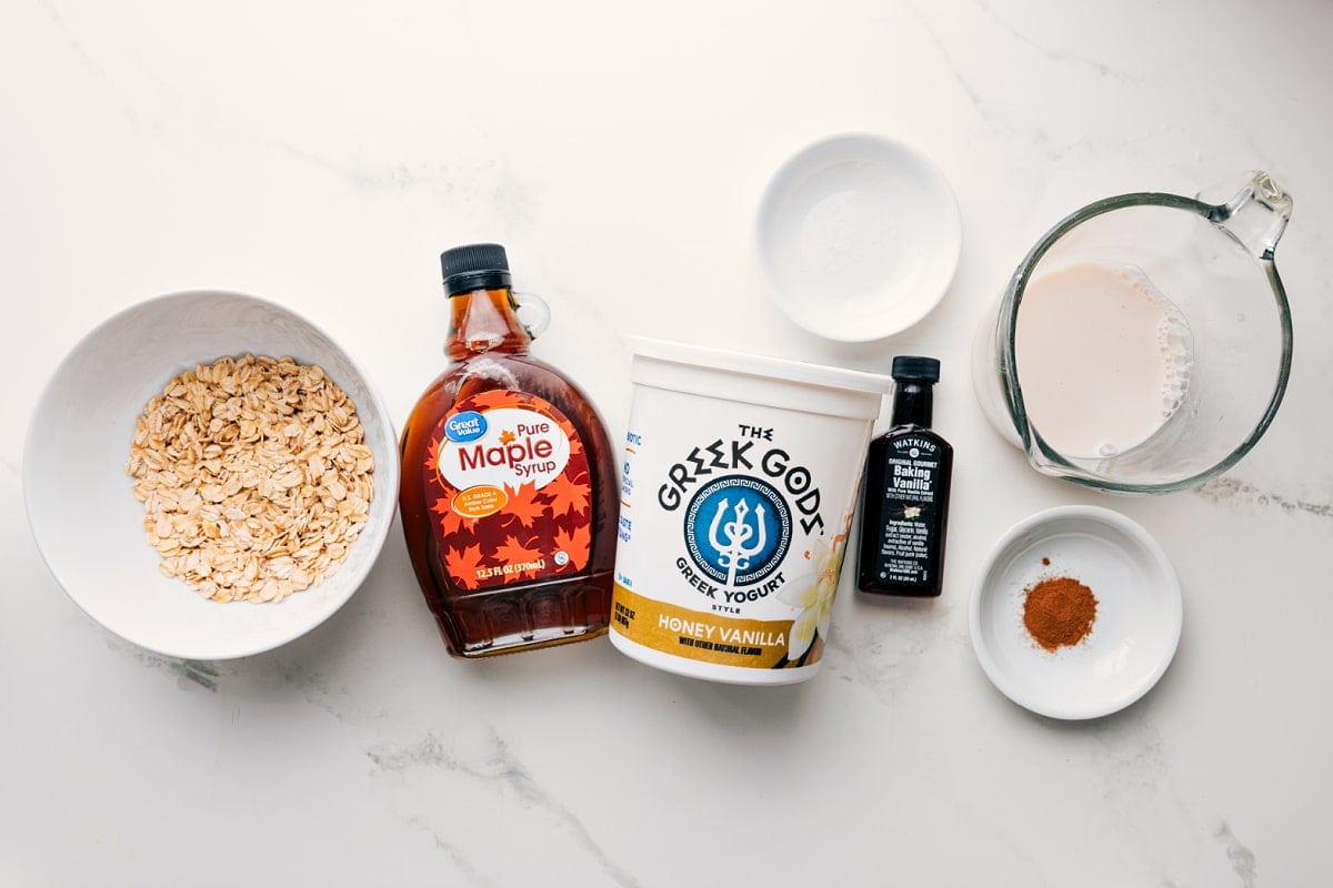 Ingredients for the base Overnight Oats Recipe, including oats, maple syrup, Greek yogurt, vanilla, cinnamon, milk, and salt.