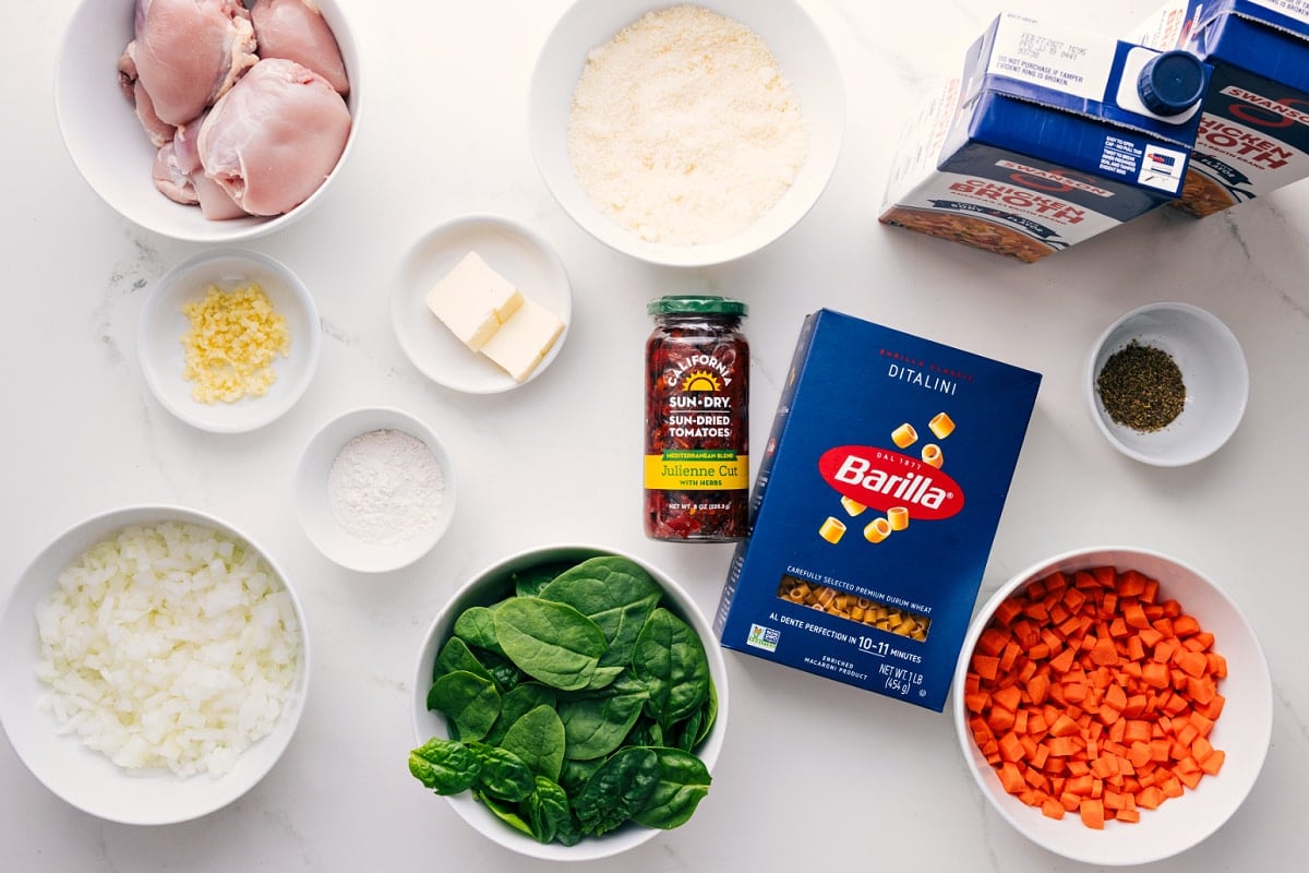 All the ingredients in this recipe prepped out for easy assembly including the chicken, onions, spinach, carrots, sun-dried tomatoes, pasta, seasonings, broth, butter.